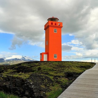Orange lighthouse Skálasnagaviti or Svörtuloft with volcano Snaefell Snaefellsjökull glacier,