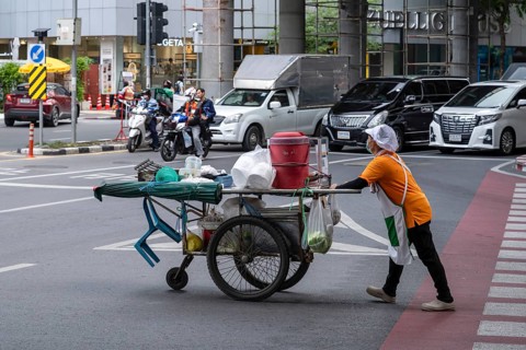 Street crossing woman with cookshop, Bangkok, Thailand