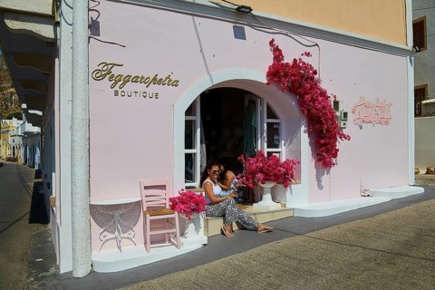 Pink boutique façade with blooming flowers, woman on the stairs, sunny and friendly atmosphere,
