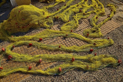 Yellow fishing nets spread on a stony ground on a sunny day, Agia Marina, Leros, Dodecanese, Greek