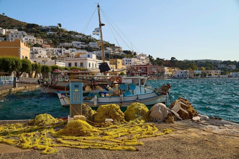Fishing nets and boats at the harbour with a view of houses on the hillside, Agia Marina, Leros,
