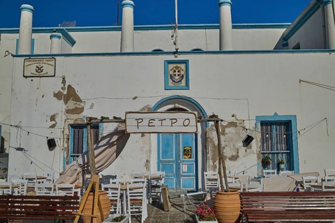 Outdoor terrace of a restaurant with blue and white façade and floral decoration, Agia Marina,
