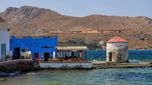 Restaurant Mylos, coastal landscape with blue buildings and a windmill by the sea, Agia Marina,