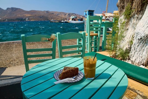 Cake and coffee on a green table by the sea, relaxing summer atmosphere with clear skies, Agia