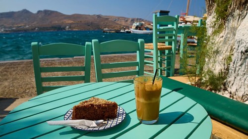 Turquoise-coloured table with drink and cake by the sea in sunny weather, relaxed atmosphere, Agia