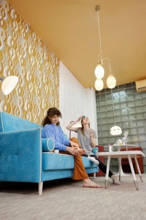In a modern living room adorned with colorful wallpaper, two women are engaged in a fun skincare