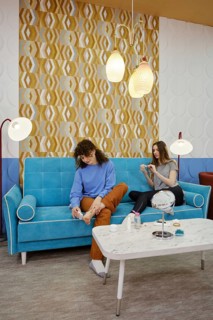 Friends spend a pleasant afternoon in a modern lounge, sitting on a turquoise sofa. They engage in
