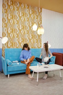 Two young women are engaged in skin care procedures at home sitting on a cozy sofa. One woman rubs