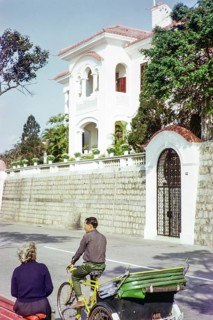 Tricycle rickshaw rider outside Portuguese colonial villa building, Avenida da Republica, Macau,