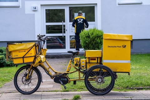 Postman, Deutsche Post, distributes the mail in an apartment building, electric tricycle, North