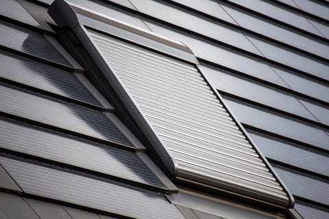 Roof window with roller shutter on a roof covered with solar tiles
