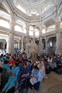 Indian woman pray between the white marble pillars around a marble elephant statue in the Adinath