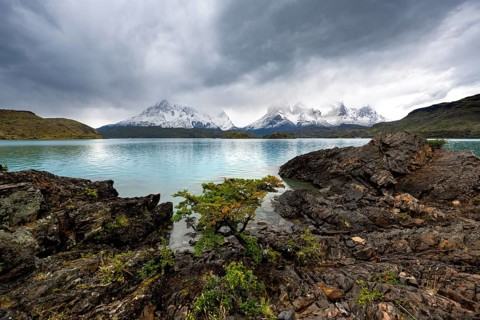 Cloudy mountain range Cuernos del Paine, shore of the blue lake Lago Pehoe in the evening light,