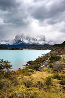 Cloudy mountain range Cuernos del Paine, shore of the blue lake Lago Pehoe in the evening light,