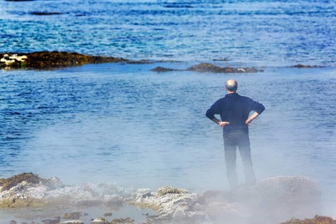 Hot spring flows into the sea, tourist on steaming rocky coast near Reykjanes, Súðavík,