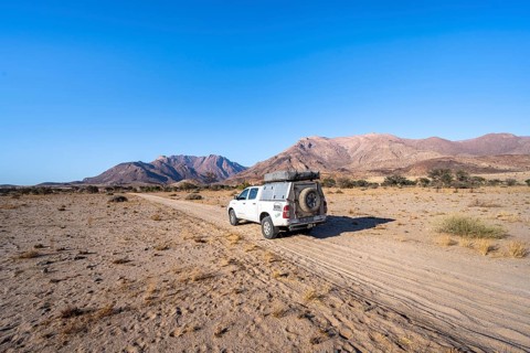 Off-road vehicle on a sandy track, desert landscape with Brandberg, Erongo, Damaraland, Namibia