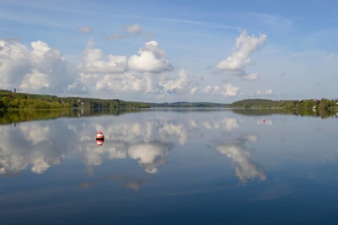 View over the Möhnesee, Möhnesee tower, red and white buoy, blue cloudy sky, reflection on the