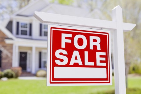 For sale real estate sign in front of beautiful house