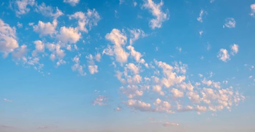 Background image for sky replacement, blue sky with loose white clouds in the evening light