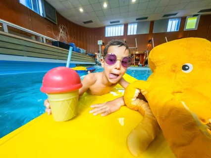 Boy with sunglasses sticking out his tongue, holding a refreshing drink and a plush toy while
