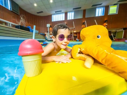 Young boy with sunglasses enjoying summer, playing with a plush octopus and an ice cream shaped toy