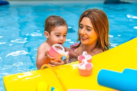 Mother and baby daughter enjoying time together, playing with pink and yellow toys while relaxing