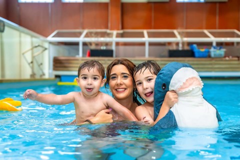 Happy family enjoying time together, playing with inflatable toy in swimming pool during summer