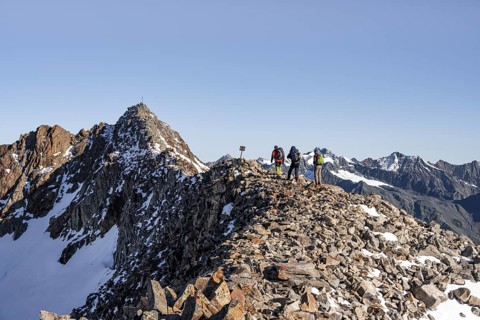 Mountaineer on a ridge, in the background summit Wilder Freiger with summit cross, Stubai Alps,