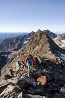 Mountaineer on a rocky ridge, ascent to the Wilder Freiger mountain peak, behind her the summit of