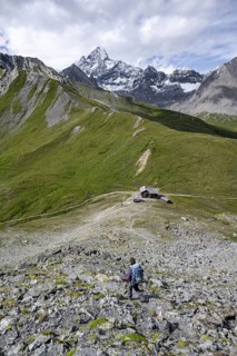 Mountaineer on hiking trail, Glorerhütte mountain hut and mountain peak in the background, Wiener
