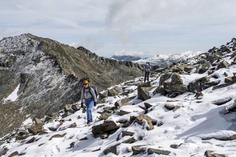 Two female mountaineers in boulder terrain with fresh snow in summer, ascent to the summit Böses