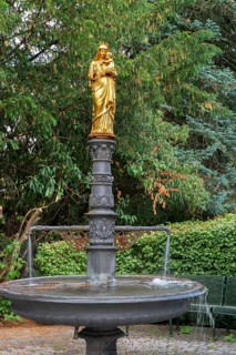 Fountain with a gilded statue of the Virgin Mary and baby Jesus, in front of St Briccius Church,