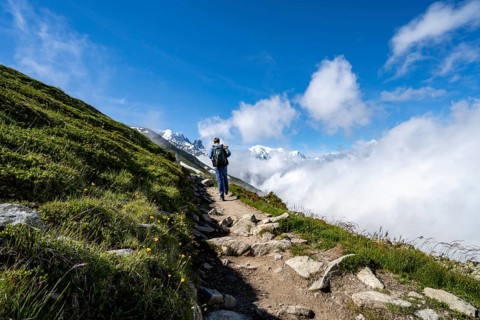 Mountaineer on a hiking trail, inversion weather situation with clouds in the valley, Chamonix,