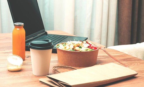 Work at home on a laptop, there is food on the table, salad, coffee and juice, delivery, there are