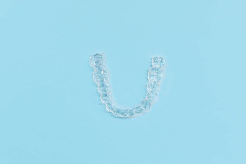 Top view of customized transparent dental teeth bite guard clear aligners for lower jaw on blue