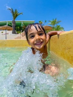 Smiling child splashing joyfully in a swimming pool, relishing carefree summer vacations at a