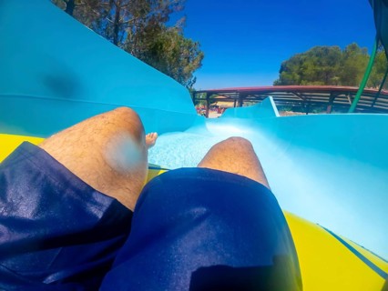 Point of view of a man sliding down a thrilling waterslide at an aquatic park, enjoying summer