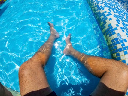 Point of view shot capturing a man relaxing in a swimming pool, legs submerged in the refreshing