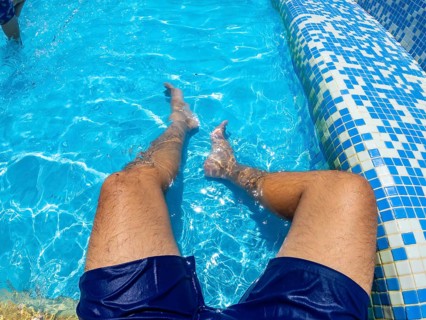 Man relaxing in a blue swimming pool, enjoying the refreshing water on a sunny summer day,
