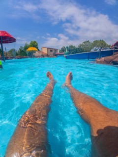 Pov shot of a man relaxing in a swimming pool at a water park, enjoying the summer sun and the