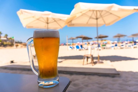 Cold beer glass sits on a table at a beach resort, offering a refreshing escape under the summer