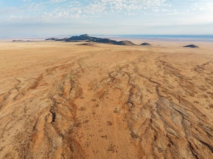 Dried-up river beds and isolated mountain ridges at the edge of the Namib Desert. Aerial view.