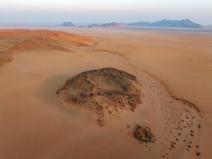 Arid plains, sand dunes and bare mountain ridges at the edge of the Namib Desert. Aerial view.