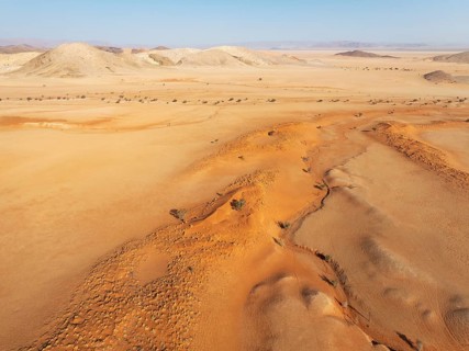 Arid plains grown with camelthorn trees (Vachellia erioloba), sand dunes and bare mountain ridges