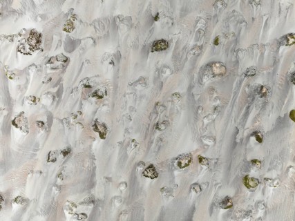 Small sand heaps form around the sparse vegetation in the Namib Desert. Aerial view. Drone shot.