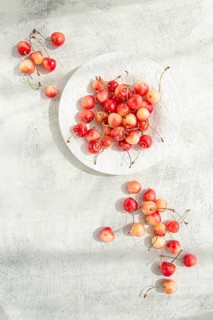 Yellow cherries on a white platter, scattered on the table, natural light, top view