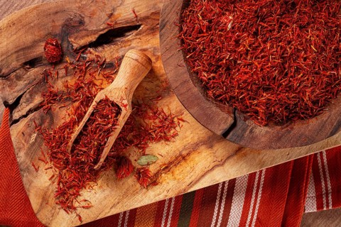 Spice saffron threads, in a wooden bowl, on a wooden table, top view, close-up