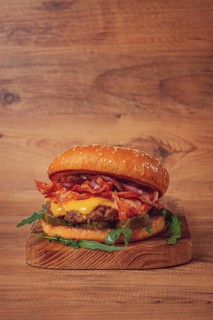 Burger with beef and bacon, with arugula and caramelized onions, pickles, sauce, homemade, no
