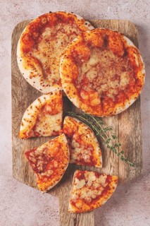 Four pizzetta Margaritas, on a cutting board, on a light gray surface, top view