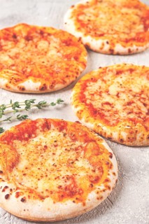 Four pizzetta Margaritas, on a light grey surface, top view